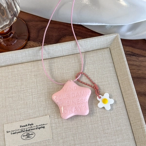 Détail du pendentif étoile rose en résine avec citation et petite fleur sur cordon