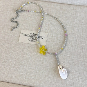 Detailed macro view of colorful beaded necklace with yellow flower and shell pendant charms