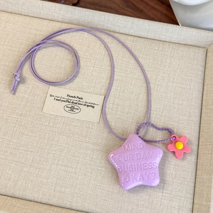 Détail d'un pendentif étoile violette gravé avec breloque fleur rose sur chaîne à billes