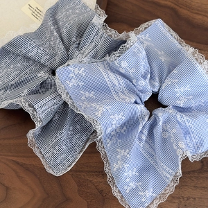 Detailed view of light blue checkered hair scrunchies with white lace embroidery edges