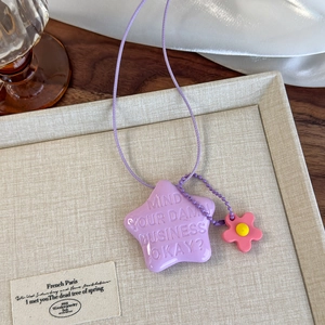 Détail macro du pendentif étoile violette avec fleur rose sur collier perlé