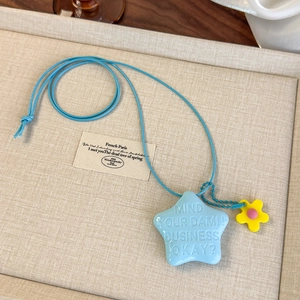 Détail du pendentif étoile bleue avec citation en relief et breloque fleur jaune