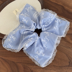 Macro detail of blue checkered scrunchie with floral embroidery and white lace edges