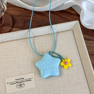 Gros plan d'un pendentif étoile bleue avec breloque fleur jaune sur un plateau texturé