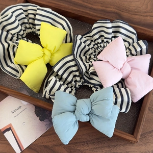 Three oversized bow hair scrunchies with black and white stripes in yellow pink and blue