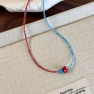 Macro detail of a handcrafted mushroom charm on a colorful red and blue beaded necklace
