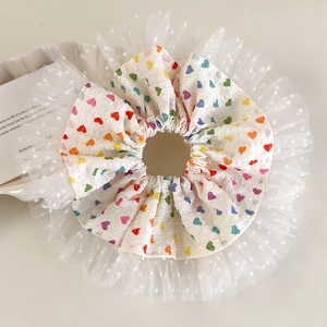 Détail d'un chouchou à motif cœurs colorés avec bordure en tulle blanc à pois délicat