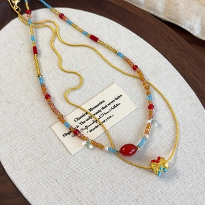 Detailed shot of ethnic style layered necklace with colorful beads and gold metal chain