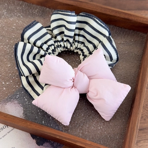 Detailed view of a soft pink puffy bow on a black and white striped hair scrunchie