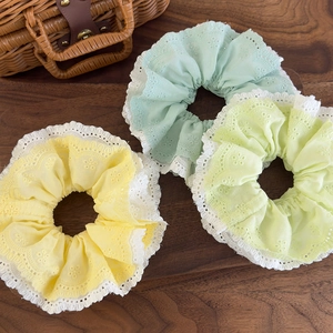 Three mint green and yellow lace-edged scrunchies on a vintage wooden background