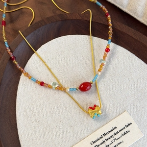 Close-up of double-layer beaded necklace with gold crown pendant on a rustic tray