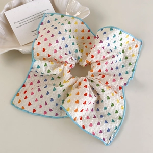 Détail du chouchou en tissu gaufré blanc avec motifs de cœurs colorés et bordure bleue