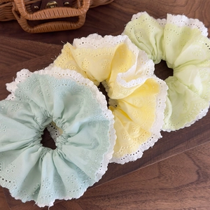 Three-piece mint green and yellow lace embroidery hair scrunchies on a wooden table