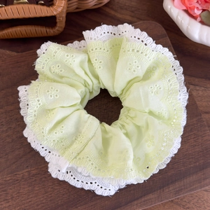 Detailed view of mint green embroidered fabric and delicate white lace on hair scrunchie