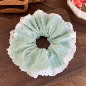Close-up of double-layered mint green lace scrunchie with floral embroidery details