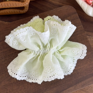 Close-up of mint green lace scrunchie with detailed floral embroidery and scalloped edges