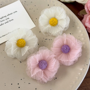 Close-up of white and pink organza flower earrings on a minimalist ceramic tray