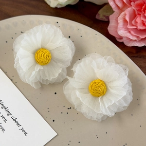 Detailed macro view of handmade white organza flower earrings with woven yellow center