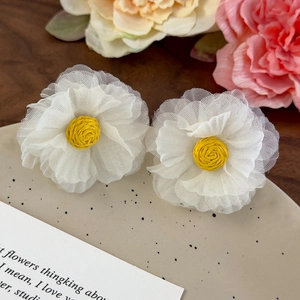 Detailed macro view of delicate white organza flower earrings with yellow woven centers
