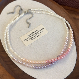 Detail of gradient pink-purple and white pearl necklaces on a wooden jewelry tray