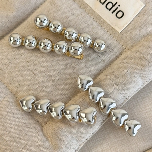 Lot de barrettes minimalistes avec cœurs et perles argentées sur tissu beige texturé