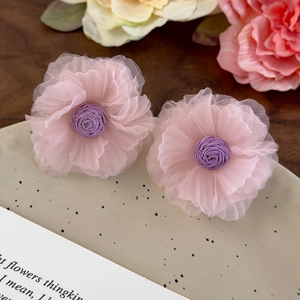 Detail of pink and purple organza flower earrings with delicate tulle petals on wood