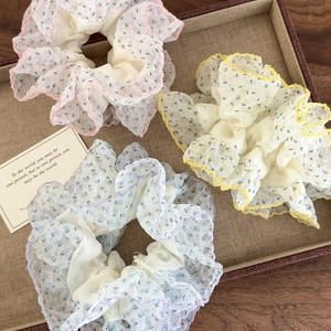 Set de chouchous en organza à fleurs rose, jaune et bleu avec bords ondulés sur plateau