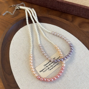 Detailed close-up of double-layer gradient pink and purple pearl necklace on wooden tray