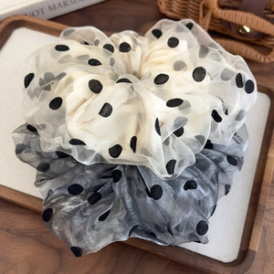Detailed view of grey and cream organza polka dot scrunchies on a wooden tray