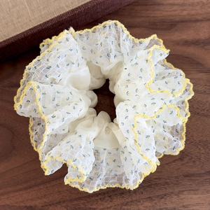 Vue détaillée du chouchou floral avec bords ondulés jaunes sur bois sombre