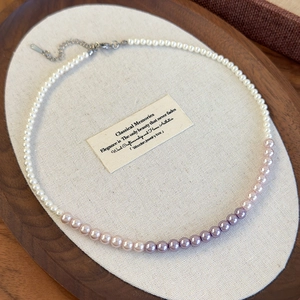 Macro detail of gradient pink and purple pearl necklace with silver lobster clasp