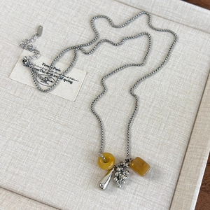 Detail of grape cluster pendant necklace with yellow stones and silver drops on tray