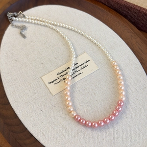 Detailed close-up of gradient pearl necklace with pink to cream tones and silver lobster clasp