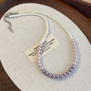 Close-up of gradient pink and purple pearl necklace with silver lobster clasp on display