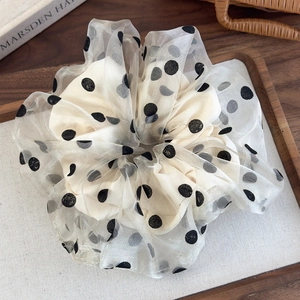 Detailed macro view of cream organza hair scrunchie with large black polka dot patterns