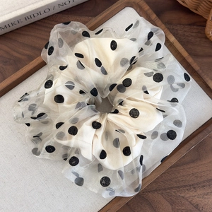 Detail of grey organza scrunchie with black polka dots on a wooden tray decor