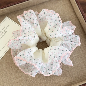 Détail d'un chouchou floral avec bord ondulé rose sur un plateau tissé pour femmes