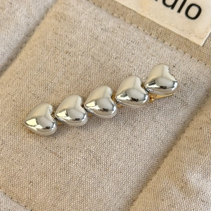 Détail macro d'une barrette à cheveux argentée en forme de cœur sur fond de toile