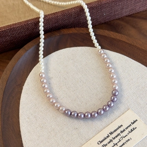 Detailed macro view of gradient pink and purple pearl necklace on a textured tray