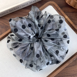 Detail of grey organza scrunchie with black polka dots on a wooden display tray