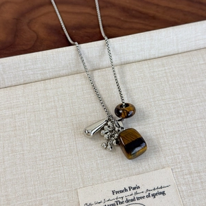 Detailed shot of tiger eye stone pendant with silver water drop and vintage box chain