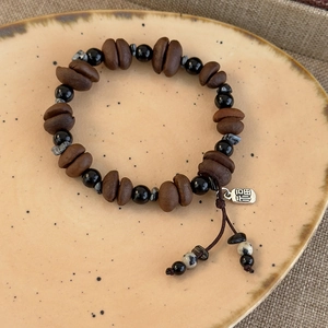 Detail of coffee bean and tiger eye stone bead bracelet with a silver Fu charm pendant