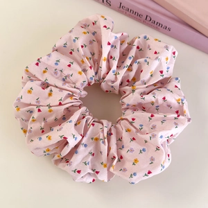 Detailed close-up of pink floral fabric scrunchie with colorful mini flower patterns