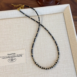 Dettaglio della collana di perline nere con distanziatori dorati e chiusura a moschettone