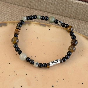 Detailed macro shot of tiger eye beads and fish-carved silver spacer on a beaded bracelet