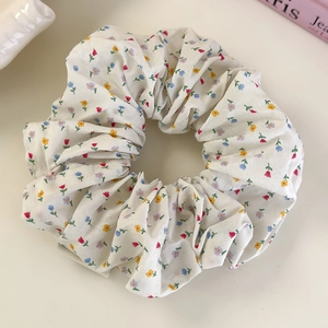 Close-up detail of floral print fabric scrunchie with soft cotton pleats and elastic band