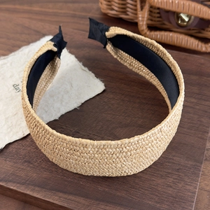 Close-up of woven straw headband with black fabric lining and elegant textured finish