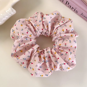 Close-up of pink floral fabric scrunchie with tiny flower pattern on a white surface