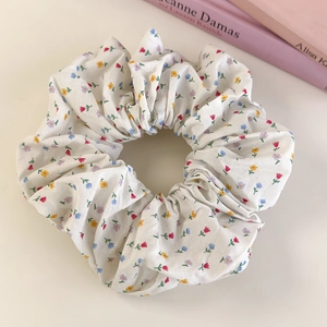 Detail of floral fabric scrunchie with colorful flower patterns on beige cotton material