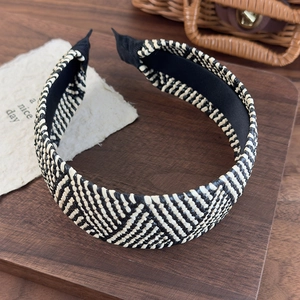 Detail shot of black and white woven straw headband texture on dark wooden tray